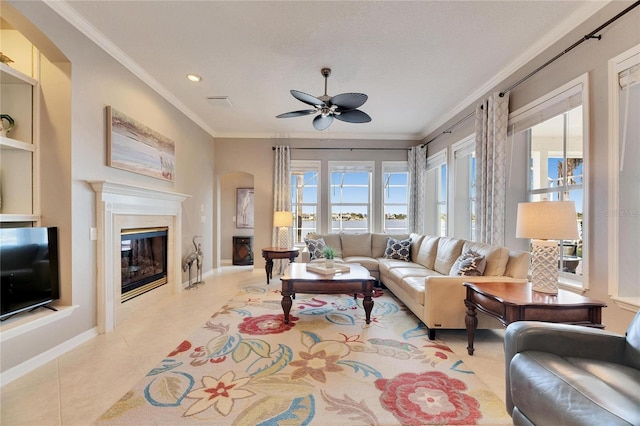 tiled living room with a high end fireplace, ornamental molding, and ceiling fan