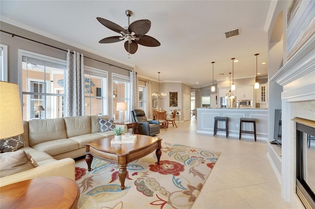 living room with ornamental molding, a premium fireplace, ceiling fan with notable chandelier, and light tile patterned floors