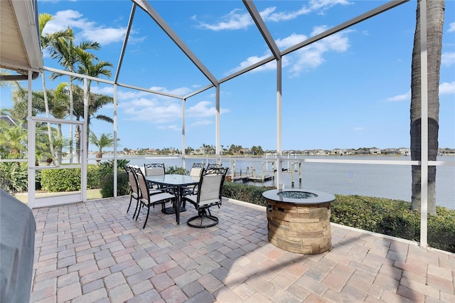 view of patio / terrace featuring a water view, an outdoor fire pit, and glass enclosure