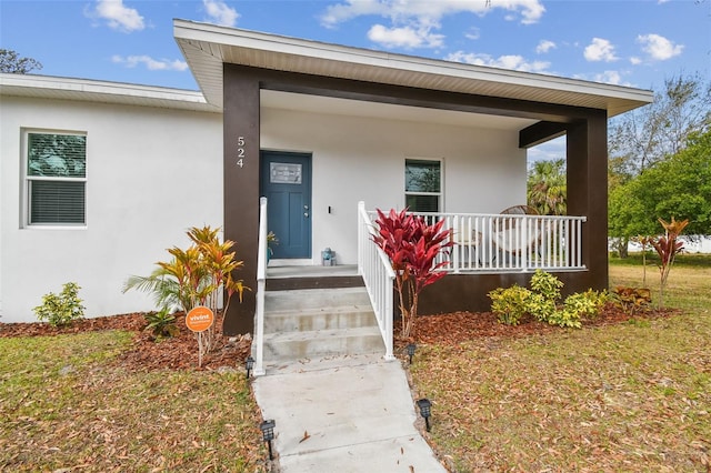 property entrance with a porch and a yard