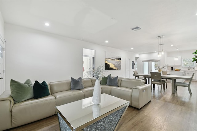 living room with sink, light hardwood / wood-style floors, and french doors