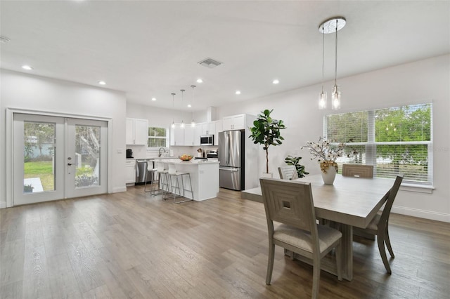 dining area featuring sink, light wood-type flooring, and french doors