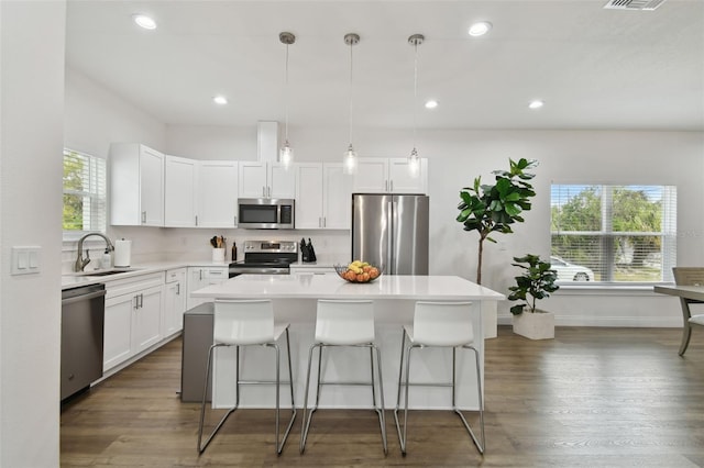 kitchen with pendant lighting, white cabinetry, sink, a center island, and stainless steel appliances