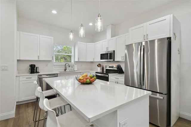 kitchen featuring a breakfast bar, sink, a center island, stainless steel appliances, and white cabinets