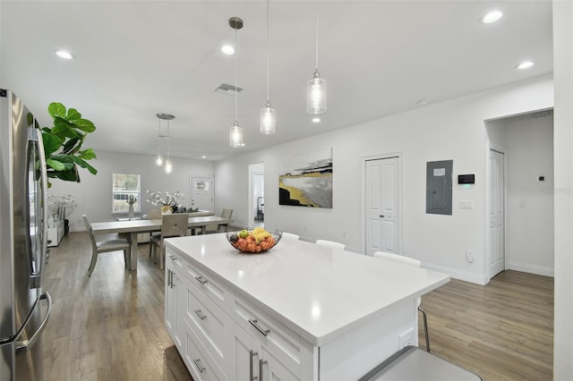 kitchen with pendant lighting, stainless steel fridge, a center island, and white cabinets