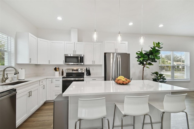 kitchen featuring stainless steel appliances, a center island, sink, and white cabinets