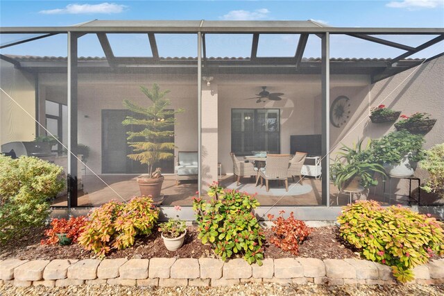 view of exterior entry featuring ceiling fan and a patio area