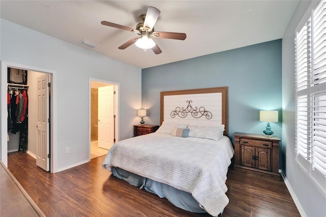 bedroom featuring connected bathroom, dark hardwood / wood-style flooring, a walk in closet, ceiling fan, and a closet