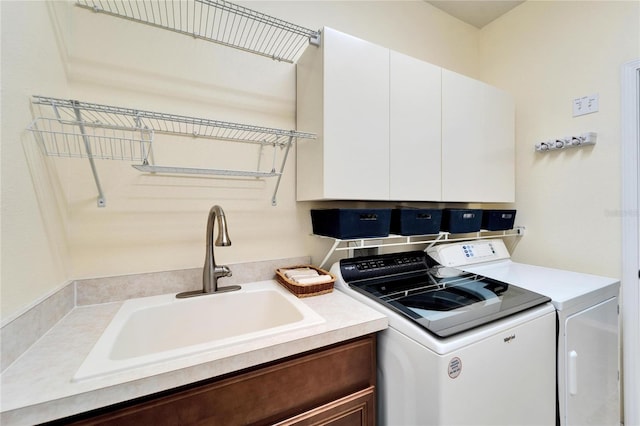 clothes washing area with cabinets, sink, and independent washer and dryer