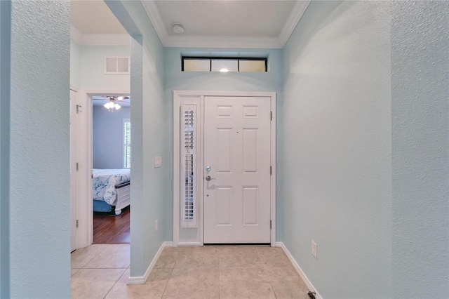 tiled foyer featuring crown molding