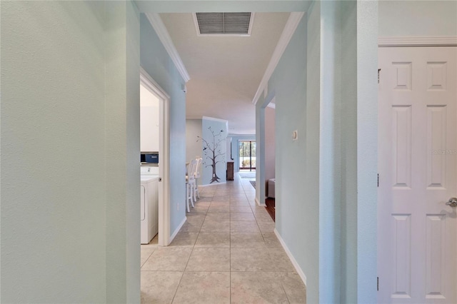 corridor with ornamental molding, washer / dryer, and light tile patterned floors