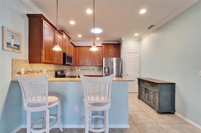 kitchen featuring tasteful backsplash, a kitchen bar, decorative light fixtures, and appliances with stainless steel finishes