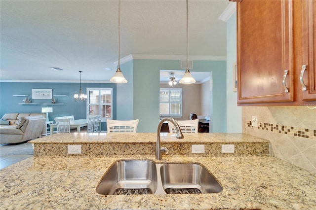 kitchen featuring pendant lighting, sink, backsplash, and crown molding