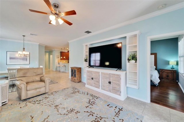 living room with crown molding, ceiling fan with notable chandelier, and light tile patterned flooring