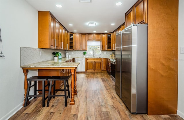 kitchen with appliances with stainless steel finishes, sink, a kitchen breakfast bar, decorative backsplash, and kitchen peninsula