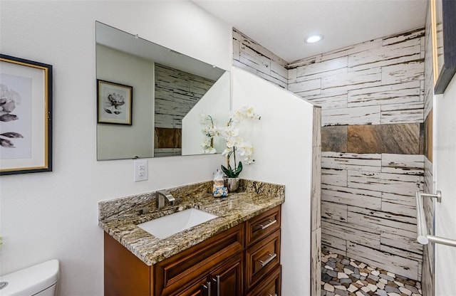 bathroom with vanity, toilet, and a tile shower