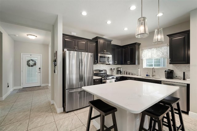 kitchen featuring sink, a breakfast bar area, stainless steel appliances, a center island, and decorative light fixtures