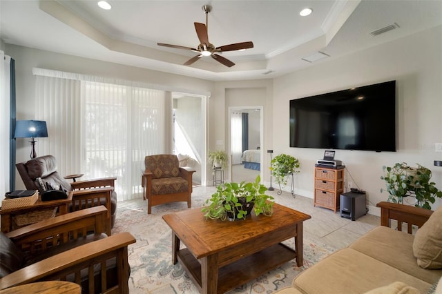 living room featuring a tray ceiling, ornamental molding, and ceiling fan