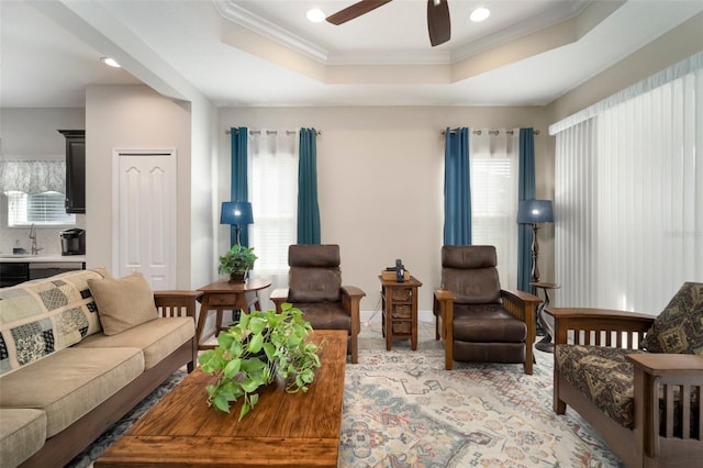 living room with ceiling fan, a raised ceiling, sink, and a wealth of natural light