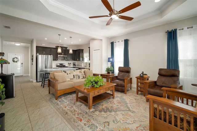 tiled living room featuring a raised ceiling, crown molding, a wealth of natural light, and ceiling fan