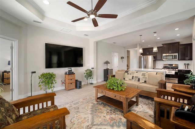 tiled living room with a raised ceiling, ornamental molding, and ceiling fan