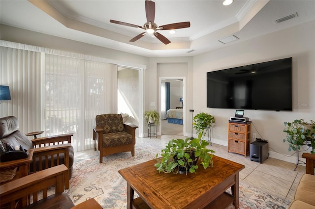 living room featuring ceiling fan, ornamental molding, and a raised ceiling