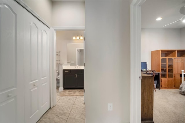 corridor featuring light colored carpet and sink