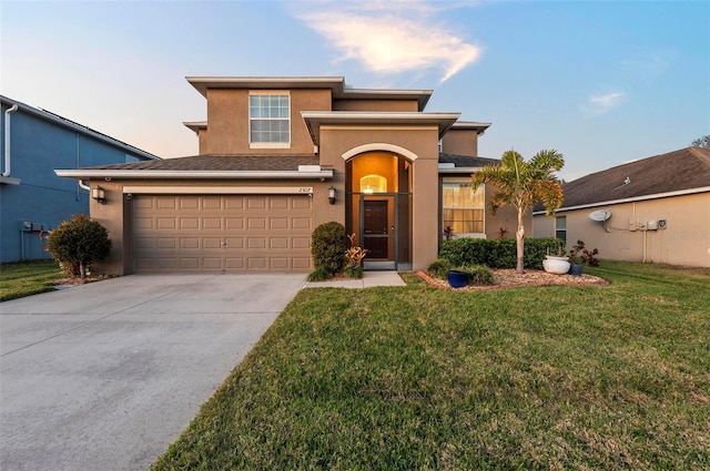 view of front of house featuring an attached garage, driveway, a front yard, and stucco siding