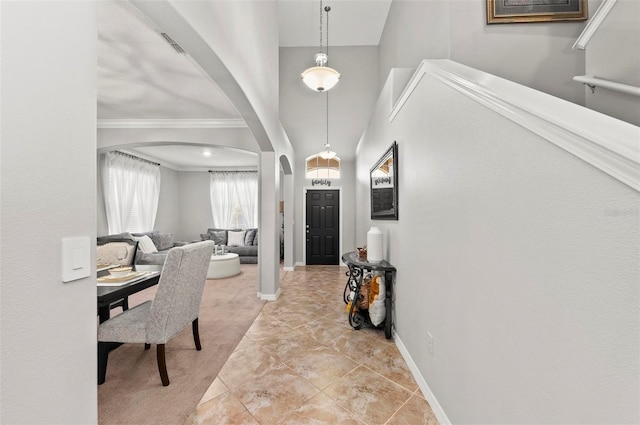 foyer featuring arched walkways, a high ceiling, visible vents, and baseboards