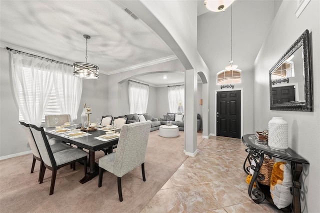 dining room featuring light tile patterned floors, baseboards, visible vents, arched walkways, and ornamental molding