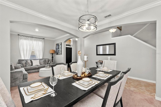 carpeted dining space featuring ornamental molding, a chandelier, and a textured ceiling