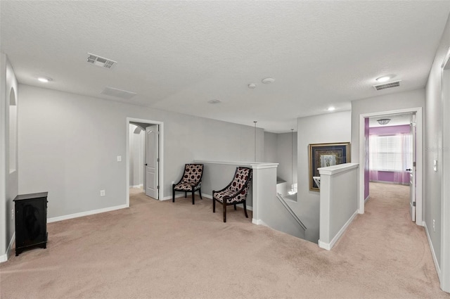 interior space with light carpet, baseboards, visible vents, and an upstairs landing