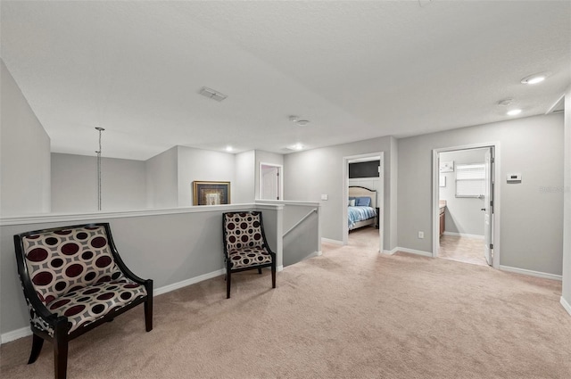 living area with light carpet, visible vents, an upstairs landing, and baseboards