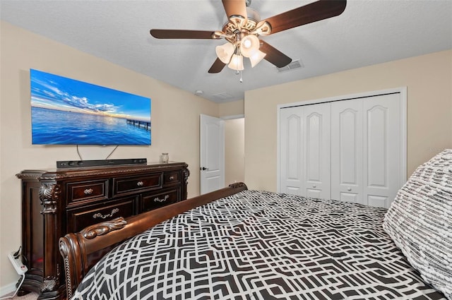 bedroom with a closet, visible vents, ceiling fan, and a textured ceiling