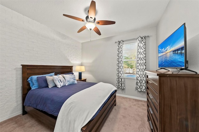 bedroom with ceiling fan, brick wall, and light carpet