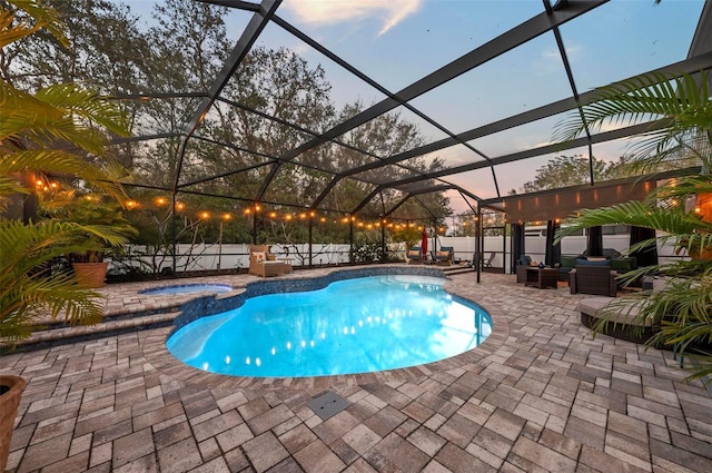 pool at dusk featuring a lanai, a fenced backyard, a pool with connected hot tub, and a patio