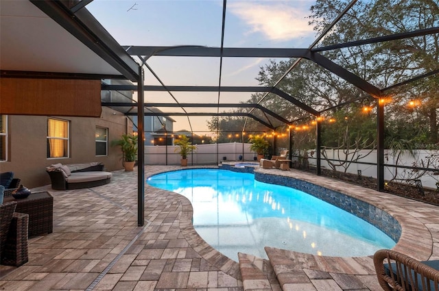 pool at dusk featuring a lanai, a fenced backyard, a pool with connected hot tub, and a patio