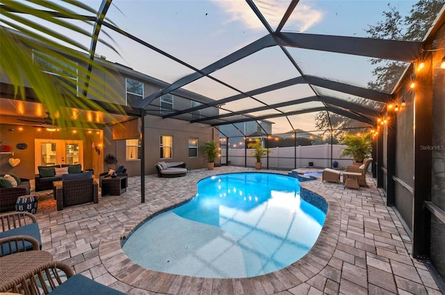 pool at dusk featuring a lanai, a patio area, and outdoor lounge area