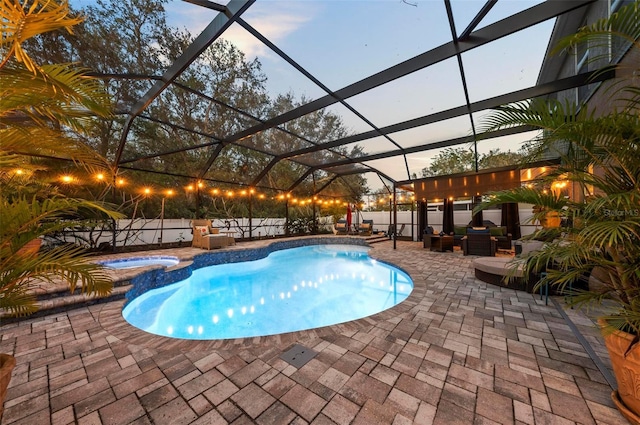 pool at dusk with an outdoor living space, an in ground hot tub, glass enclosure, and a patio area