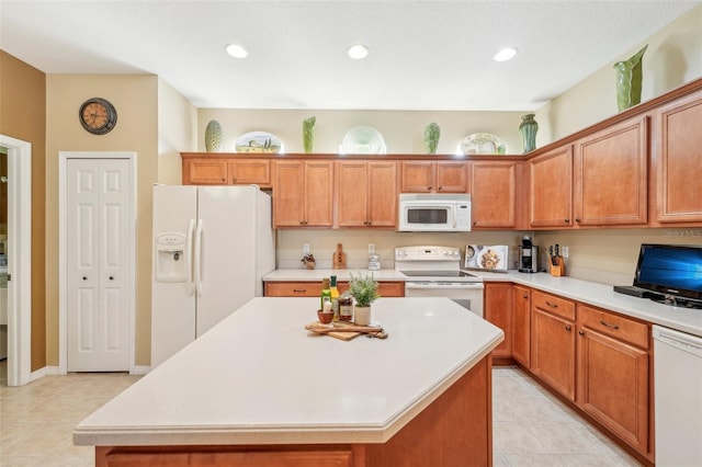 kitchen featuring a kitchen island, light tile patterned floors, and white appliances