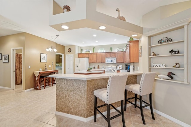 kitchen with washer / dryer, a kitchen bar, light tile patterned floors, kitchen peninsula, and white appliances