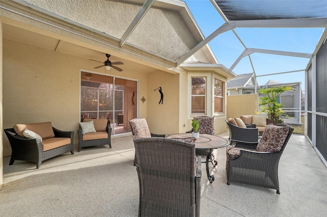 view of patio / terrace featuring an outdoor living space, ceiling fan, and glass enclosure