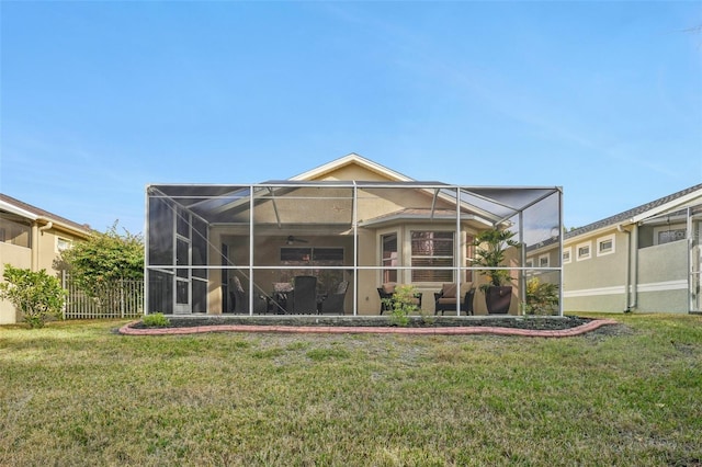 back of house featuring ceiling fan, glass enclosure, and a lawn