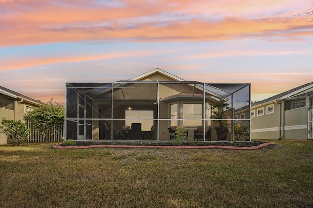 back house at dusk featuring a yard and a lanai