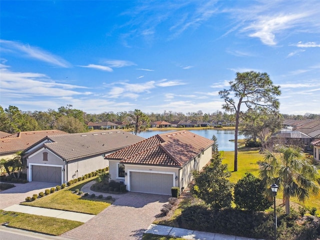 mediterranean / spanish home featuring a water view, a garage, and a front lawn