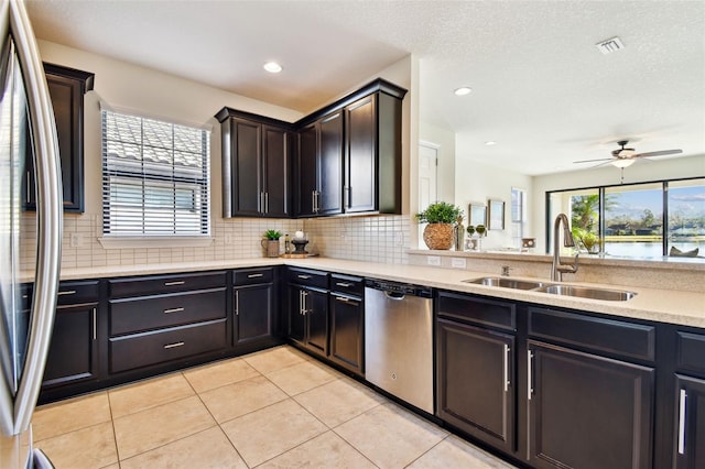 kitchen with stainless steel appliances, decorative backsplash, light tile patterned flooring, ceiling fan, and sink