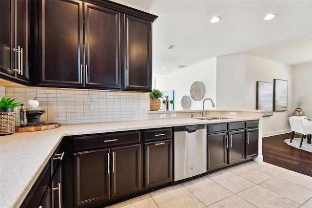 kitchen featuring sink, decorative backsplash, light tile patterned floors, stainless steel dishwasher, and dark brown cabinetry