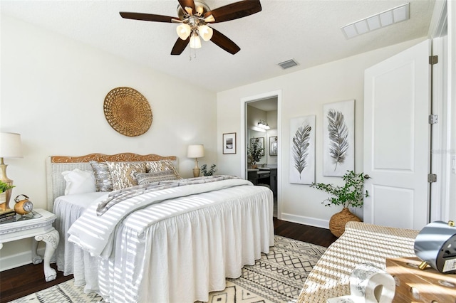 bedroom featuring dark hardwood / wood-style flooring, ensuite bath, and ceiling fan