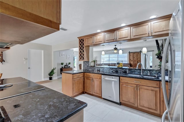 kitchen featuring sink, hanging light fixtures, dark stone countertops, appliances with stainless steel finishes, and kitchen peninsula