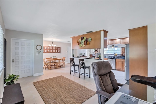 interior space with a breakfast bar, tasteful backsplash, decorative light fixtures, light tile patterned floors, and appliances with stainless steel finishes